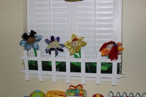 Colorful flower stick puppets on nursery window sill.